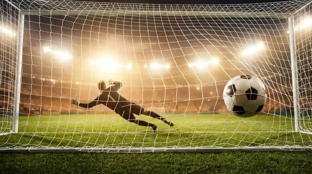 Pallone da calcio che entra in rete con il portiere battuto, visto da dietro la porta su un campo in erba naturale illuminato